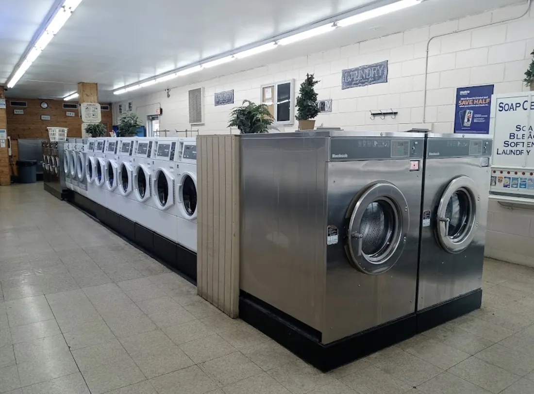 Stainless front-load washers beside a long row of white washers and the soap center