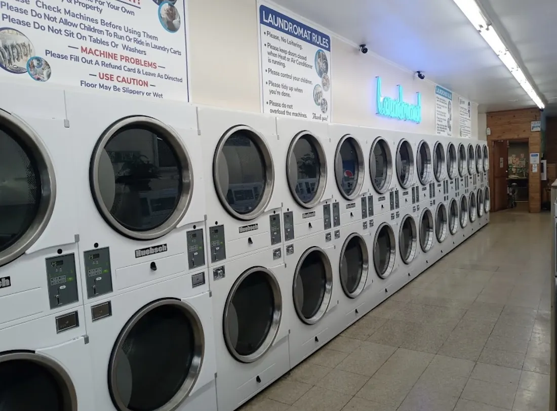 A long wall of stacked dryers under a blue neon sign